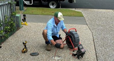 Worker Unblocking A Drain On A Driveway